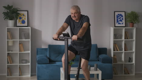 sport-and-healthy-lifestyle-at-middle-and-old-age-man-is-training-on-stationary-bike-at-home-keeping-fit-and-health-of-body